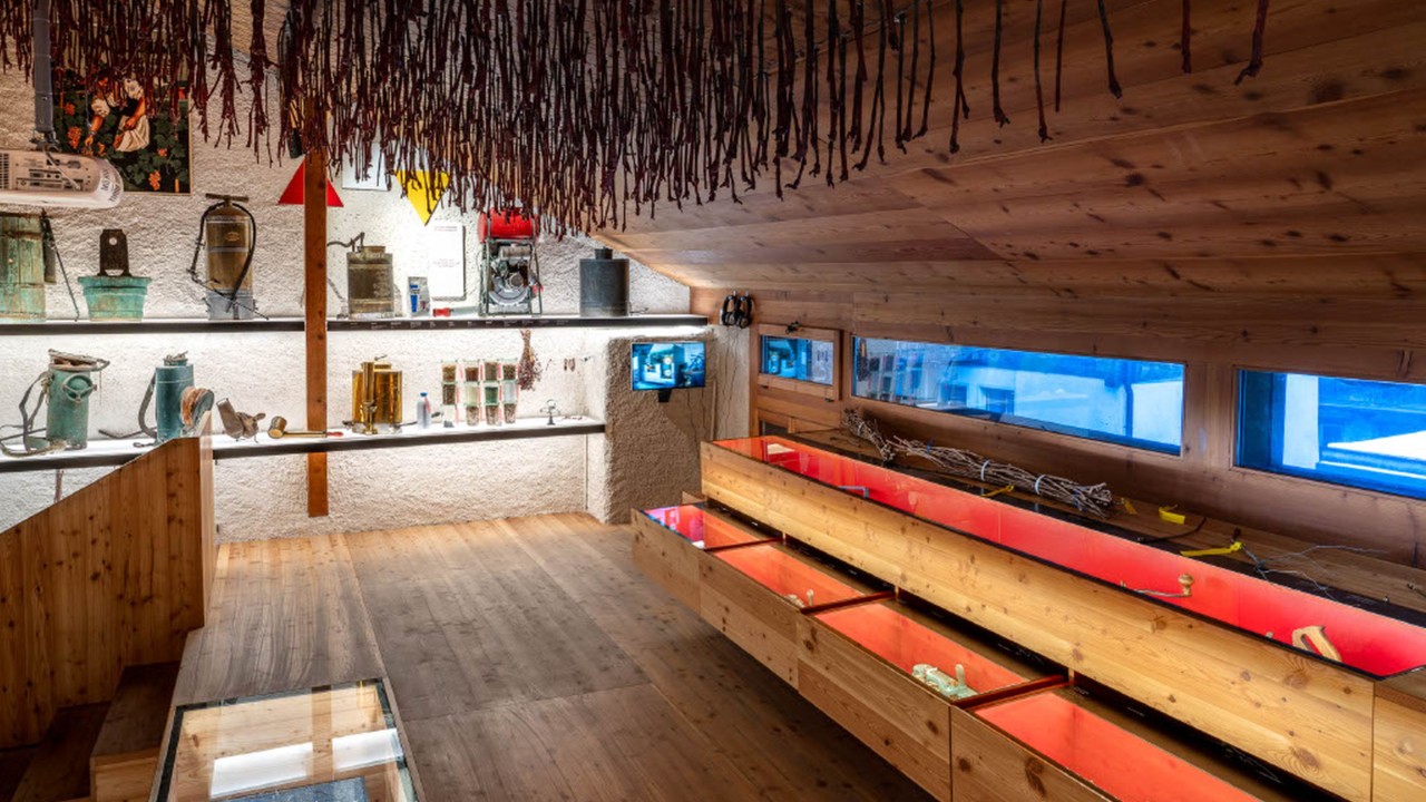 Sous les combles du musée de Salquenen, habillés de boiseries en pin, une exposition d’outils et d’accessoires traditionnels de la vigne habille la paroi du fond. À droite, des coffres-vitrines alignés dévoilent de nombreux objets.