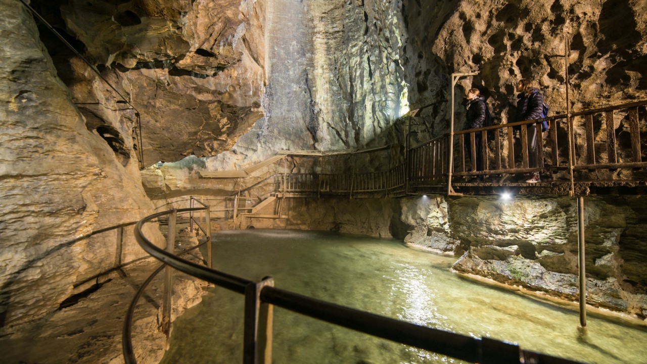 Depuis la passerelle qui longe une paroi rocheuse à gauche de la grotte, on aperçoit sur la droite un lac aux eaux limpides et aux reflets dorés. Deux amas rocheux le surplombent à gauche et à droite et laissent apparaître plus loin une large et haute salle. Des spots éclairent cette grotte. Une autre passerelle longe également la paroi de droite. L’ambiance est mystérieuse.