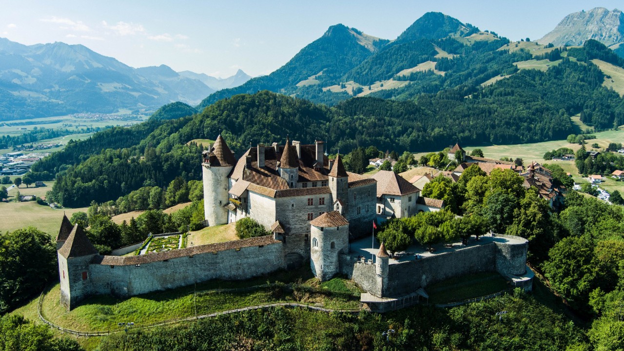 Gruyères Castle from above, with mountains in the background.